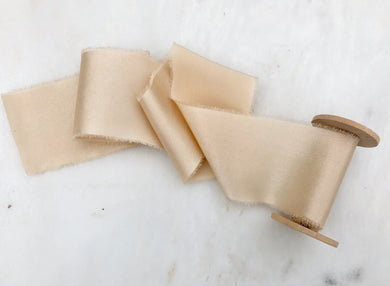 handmade and hand dyed silk charmeuse ribbon with a hand torn edge on a wooden spool