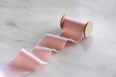 handmade and hand dyed pink vegan bamboo with a hand torn frayed edge on a wooden spool