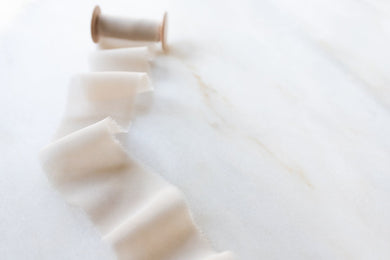 close up of a 2 inch wide ivory silk chiffon ribbon on a marble surface